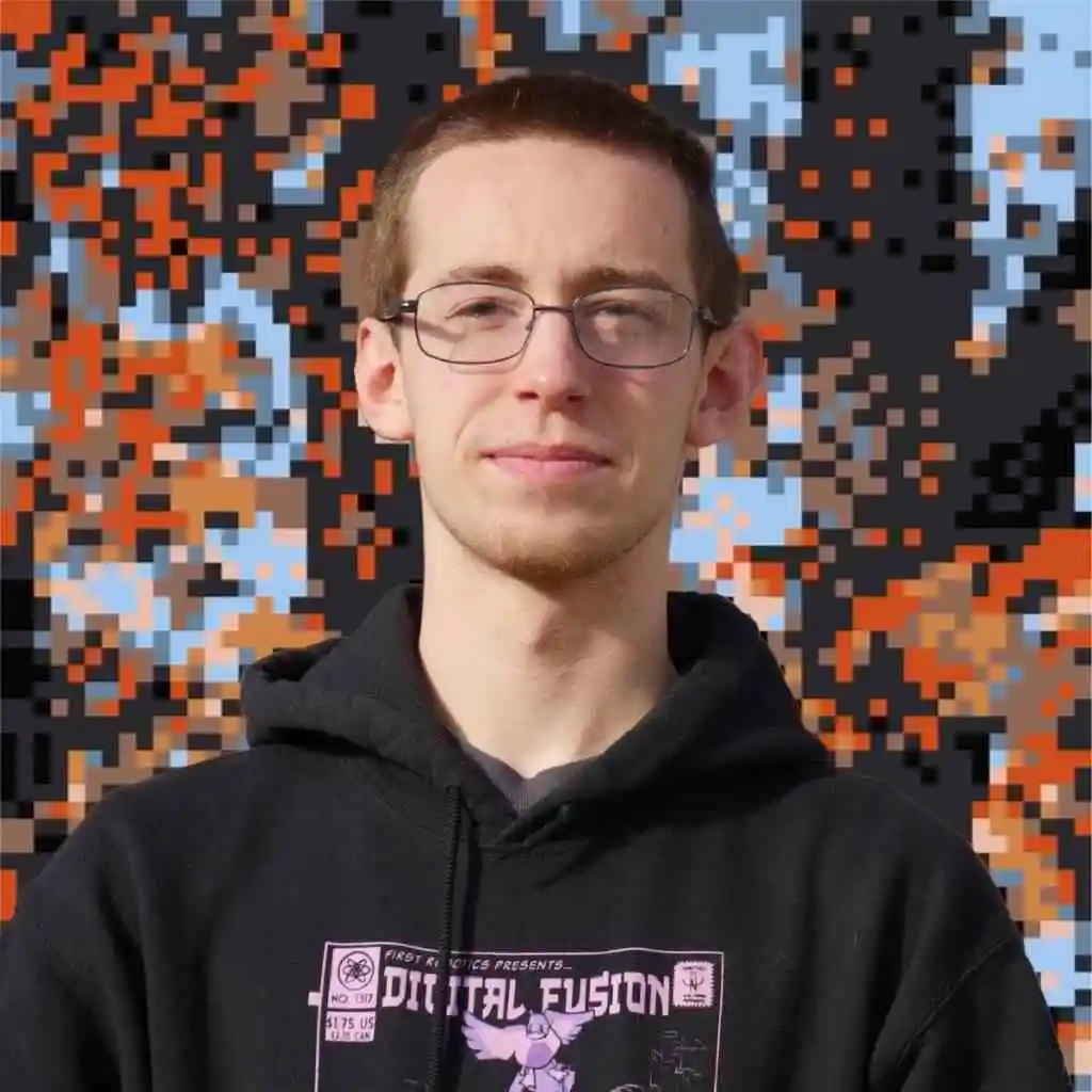 A photo of kieran wearing a black hoodie set against chaotic, mosaic-like background of orange, blue, brown, and black pixels.